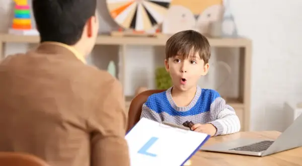 Un niño sorprendido interactúa con un logopeda que es un profesional de la comunicación.