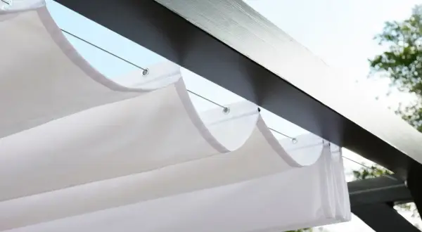 Vit markisduk hänger i vågor under en mörk pergola, perfekt för en solig dag.