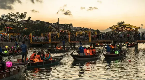 Boote mit bunten Laternen auf einem Fluss in Vietnam bei Sonnenuntergang. Ein toller Tipp für deine Vietnam Reise!