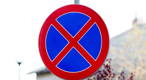 Znak zakazu parkowania przed znakiem informuje, że postój pojazdów jest zabroniony.