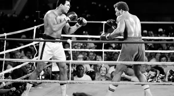 Muhammad Ali in the ring, a pivotal moment in his life events. He faces his opponent, the crowd watching intently.