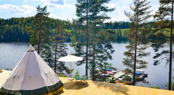 En stor tipi på en träaltan vid en sjö. Perfekt för natur camping med båtar vid bryggan.
