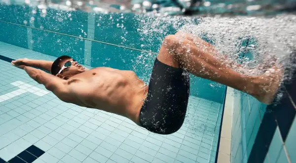 Schwimmer mit Brille und Badehose treibt unter Wasser. Das extensives intervalltraining fordert ihn.