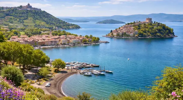 Marta al lago di Bolsena, con borghi pittoreschi, un porto turistico e colline verdi.