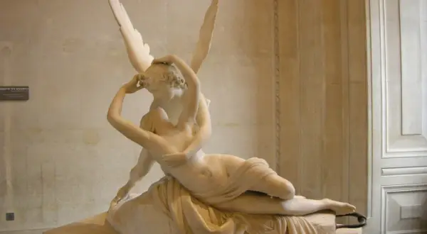 Een beeld van Eros, de god van de liefde, die Psyche kust. De vleugels van Eros zijn wijd gespreid.