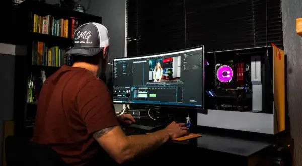 Uomo con cappellino SMG impegnato in un corso di editing video, lavora su un computer con software di montaggio.