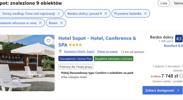 Białe leżaki i parasole na plaży przed budynkiem hotelu.