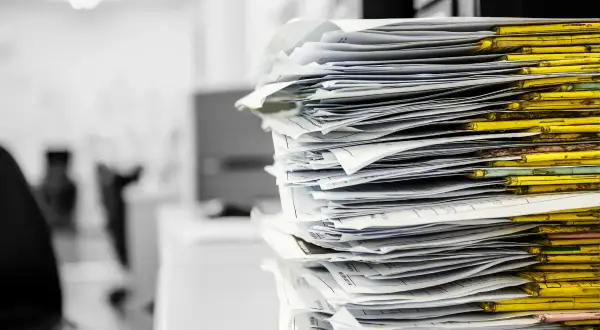 Stos papierów w żółtych segregatorach. Czas na porządki, co to znaczy? Niezwłocznie!