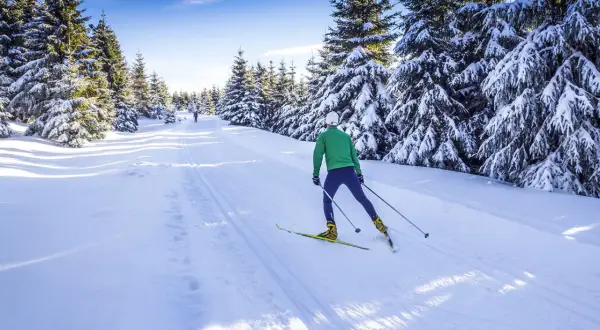 Langlauf-Spaß im verschneiten Riesengebirge, Tschechien. Ein Mann gleitet auf Skiern durch eine sonnige Winterlandschaft.