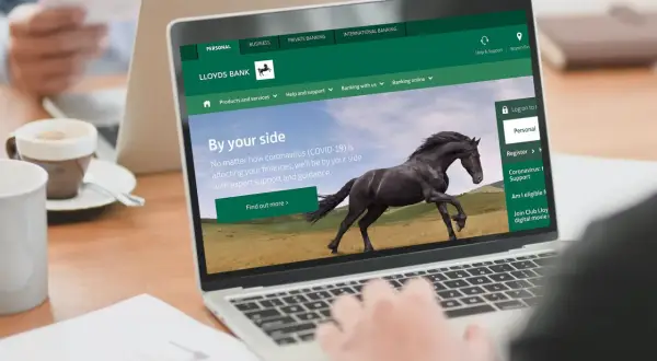 Strona internetowa Lloyds Bank z hasłem "By your side" i czarnym koniem. Dostępne opcje: Personal, Business, Private Banking.