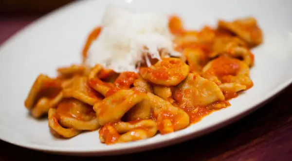Orecchiette pugliesi con sugo rosso e una spolverata di formaggio grattugiato, un piatto che sa di casa e tradizione.