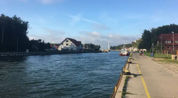 Spacerem nad jeziorem Sarbsko, widać kanał, budynki i łodzie.