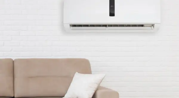 Condizionatore senza motore esterno come funziona: un'unità bianca a parete sopra un divano beige, con un display digitale che mostra 24 gradi.