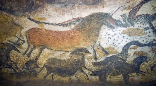 Przykłady malarstwa prehistorycznego: malowidła naskalne przedstawiające zwierzęta, takie jak konie i bizony, namalowane naturalnymi barwnikami na ścianie jaskini.