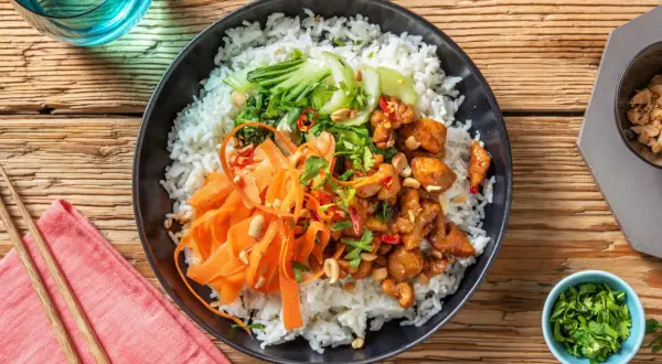 En läcker donburi med kyckling, ris, strimlad morot, pak choi och jordnötter.