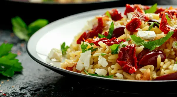 Salade de pâtes orzo avec tomates séchées, mozzarella fraîche et basilic. Un plat coloré et savoureux.