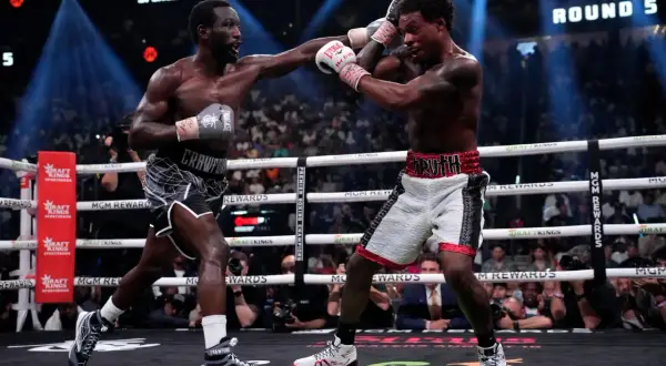 Two boxers exchange punches in a tense moment, with the crowd watching intently. The scoreboard shows "ROUND 5," highlighting the ongoing battle for boxing scoring punches.
