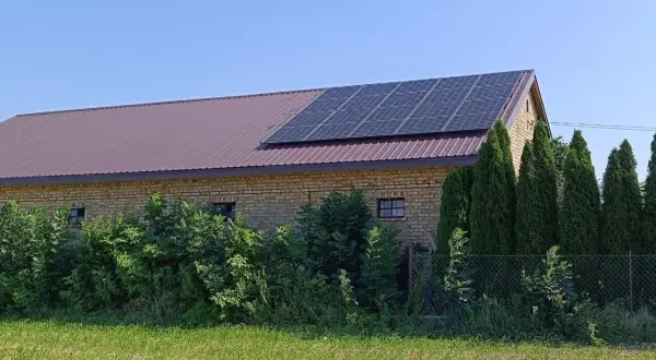 Panele fotowoltaiczne na dachu ceglanego budynku, symbolizujące sprzedaż energii z fotowoltaiki.