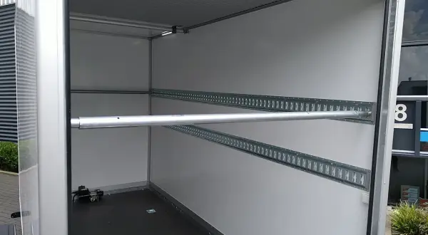 Intérieur de remorque avec rails d'arrimage et barre transversale, idéal pour le règlement chargement remorque.