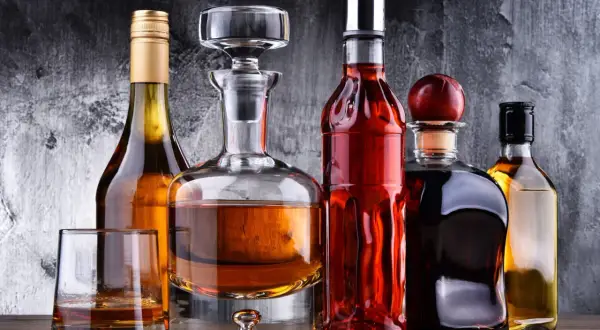 Karafka i butelki z bursztynowym płynem, być może wyśmienity brandy, stoją na drewnianym blacie.