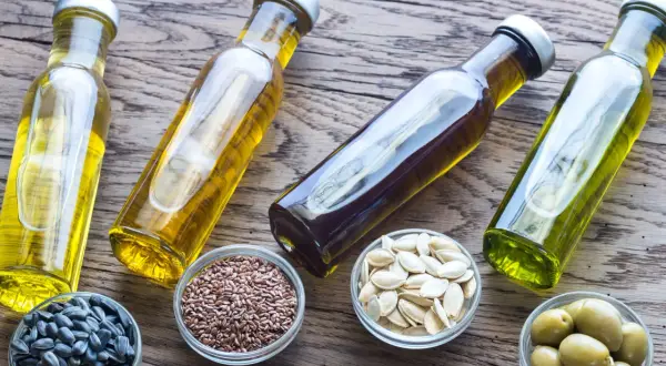 Bottiglie di olio e ciotole con semi di girasole, semi di lino, semi di zucca e olive. Quale sarà il miglior olio per friggere?
