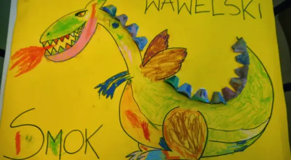 Kolorowa praca plastyczna przedstawiająca zielonego smoka wawelskiego ziejącego ogniem. Napisy "SMOK" i "WAWELSKI" dopełniają dzieło.