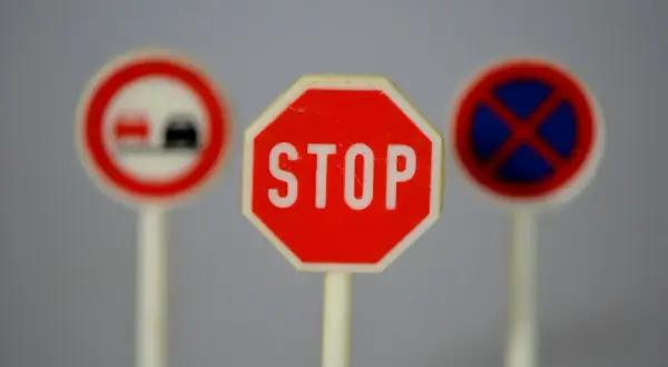 Trzy miniaturowe znaki drogowe: STOP, zakaz wyprzedzania i zakaz zatrzymywania się. Idealne do nauki przepisów ruchu drogowego.