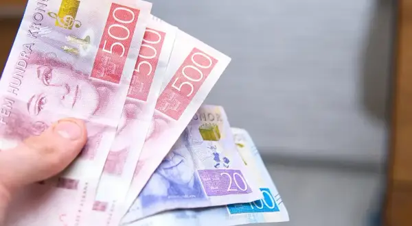 Dłoń trzyma banknoty 500 koron szwedzkich. To pokazuje, jaka jest waluta w Szwecji.
