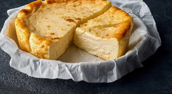 Un délicieux fiadone, recette corse, est servi sur du papier sulfurisé. Sa croûte dorée et sa texture crémeuse invitent à la dégustation.