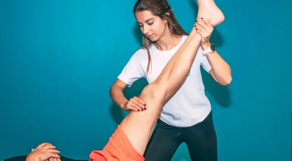 Une kinésithérapeute étire le muscle quadriceps d'un patient.