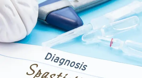 Medyczne narzędzia i ampułki na niebieskim tle. Na papierze widnieje napis "Diagnosis Spastyczność mięśni".