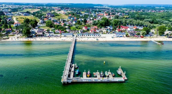 Mechelinki: warto jechać! Widok na molo, plażę i urokliwą nadmorską miejscowość.