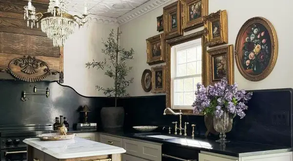 A luxurious kitchen with a crystal chandelier, ornate wood paneling, and a collection of framed floral paintings, evoking the grandeur of Victorian houses.
