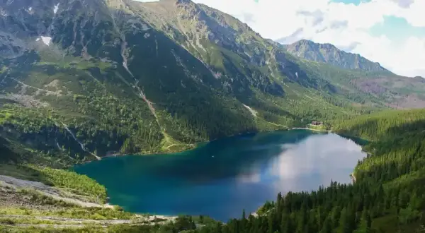Malowniczy widok na Morskie Oko, idealne miejsce na górską trasę. Otoczone zielonymi lasami i skalistymi szczytami Tatr.