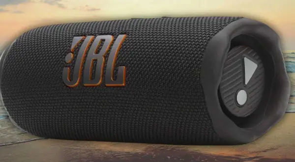 Enceinte JBL noire sur une plage. Découvrez comment fonctionne une enceinte JBL pour une expérience sonore immersive, même en extérieur.