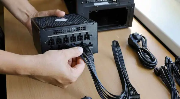 Persona conecta cables a una fuente de alimentación de PC. Es el momento de comprobar fuente de alimentación pc.