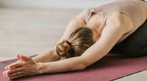 Une femme en posture de yoga, bras tendus, sur un tapis. Un moment pour apprendre comment s'apaiser.