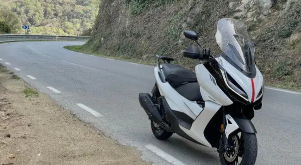 Scooter Zontes blanca en carretera sinuosa. Opiniones sobre motos Zontes: diseño moderno y ágil para rutas de montaña.