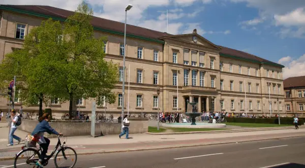 Großes Universitätsgebäude mit Brunnen und Studenten. Hier kann man Zahnmedizin studieren.