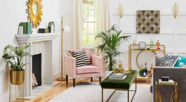 A living room with a pink armchair, gold accents, and a fan pattern artwork, showcasing what is art deco style with its geometric shapes and luxurious feel.