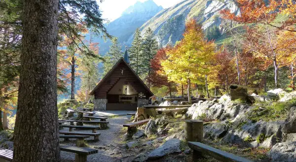Holzhütte mit Bänken und bunten Bäumen im Herbst. Perfekt für eine Seealpsee Wanderung.
