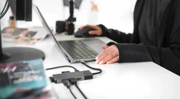 Praca zdalna i turystyka w jednym. Ktoś planuje podróż, przeglądając oferty na laptopie, podłączonym do hubu USB.