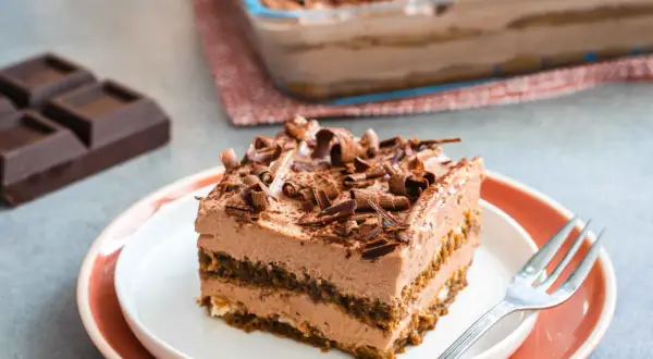 Una fetta di goloso tiramisù al cioccolato e mascarpone, guarnito con riccioli di cioccolato fondente.