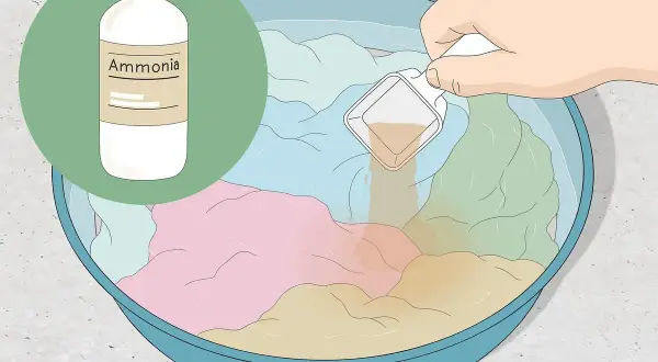 Eine Hand gibt eine Messlöffel-Menge einer Flüssigkeit in eine Schüssel mit bunten Kleidungsstücken und Wasser. Die Flüssigkeit hilft, den **Geruch aus Kleidung entfernen**.