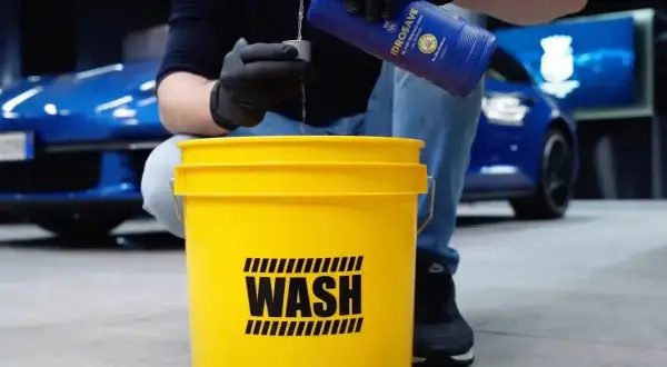 Przygotowanie do mycia samochodu na myjni: nalewanie płynu do wiadra z napisem "WASH".