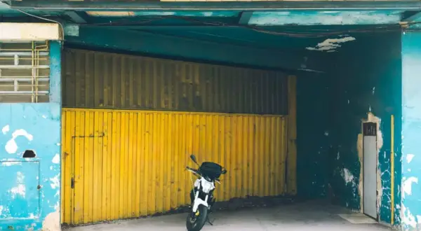 Moto aparcada frente a una cochera con puerta amarilla, se puede aparcar en una cochera sin vado.