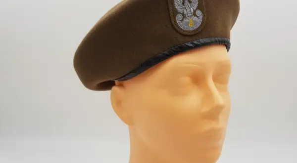 Brązowy beret wojskowy z orłem, jeden z rodzajów czapek wojskowych, prezentowany na manekinie.