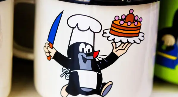 Krecik w czapce kucharskiej z nożem i tortem, jak z bajek z dzieciństwa, na kubku.