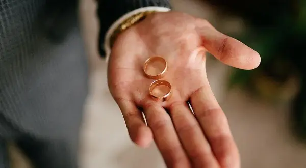 Dos anillos de oro descansan en una mano abierta, listos para ajustar el anillo y sellar un compromiso.