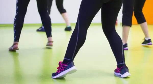 Ludzie w legginsach i butach sportowych ćwiczą na sali. Może właśnie dlatego buty skrzypią?